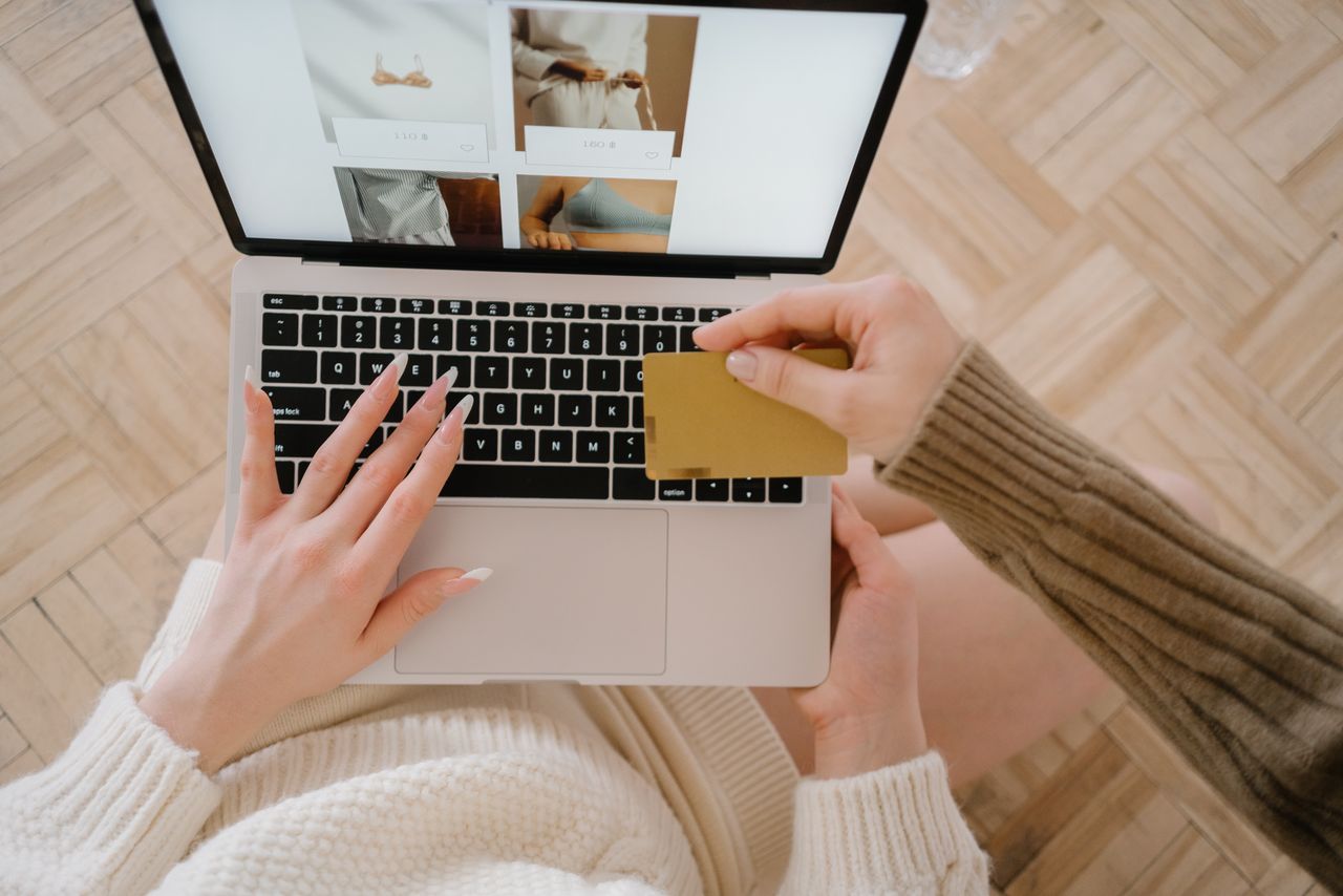 Personne faisant des achats en ligne avec un ordinateur portable et une carte de crédit, mettant en avant la simplicité du commerce électronique.